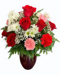 Bouquet of red roses, white flowers, and pink carnations in a vase 