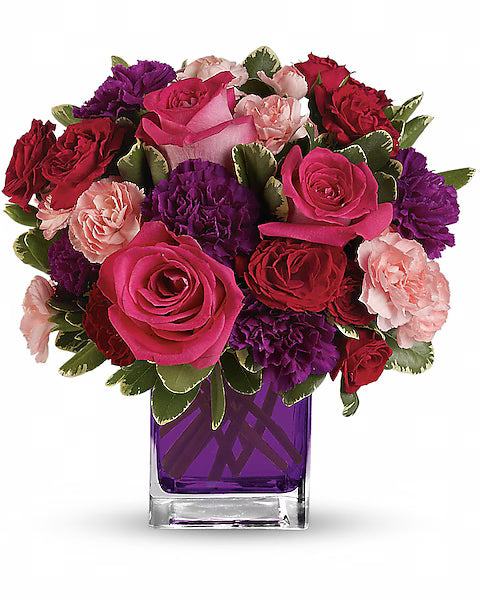 Colorful flower arrangement with red, pink, and purple flowers in a clear vase
