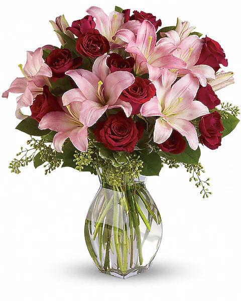 Bouquet of pink lilies and red roses in a clear vase