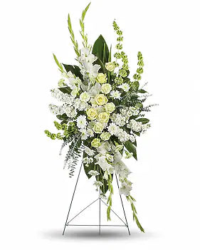 A large floral arrangement in a tall metal stand, featuring white and pale yellow flowers with green foliage, photographed on a clean white background.