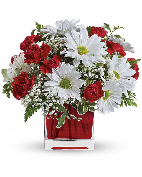 Bouquet of red and white flowers in a clear vase with a red base 