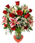 Bouquet of red roses and pink lilies in a clear vase