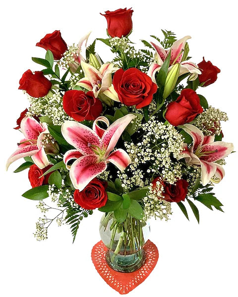 Bouquet of red roses and pink lilies in a clear vase